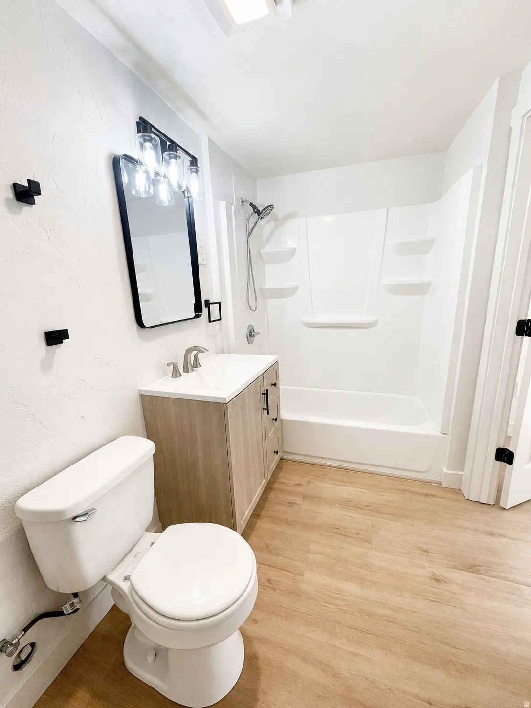 Full bathroom in basement featuring a light wood-finish vanity with a white countertop and rectangular sink
