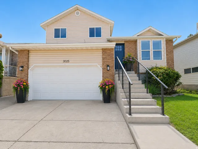 Split-level facade featuring beige siding and brick accents--virtually staged.