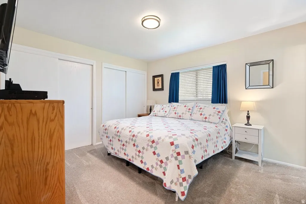 Carpeted bedroom with a window featuring horizontal blinds and blue drapes