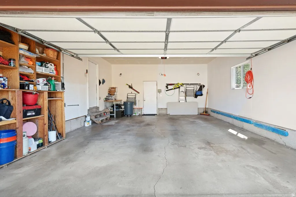 Spacious garage with concrete flooring, built-in wooden shelving, and a large window