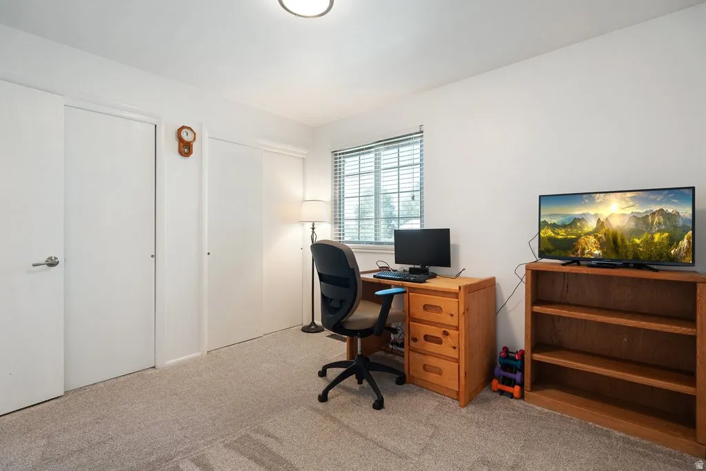 Light gray carpeted room with white walls and a window featuring horizontal blinds