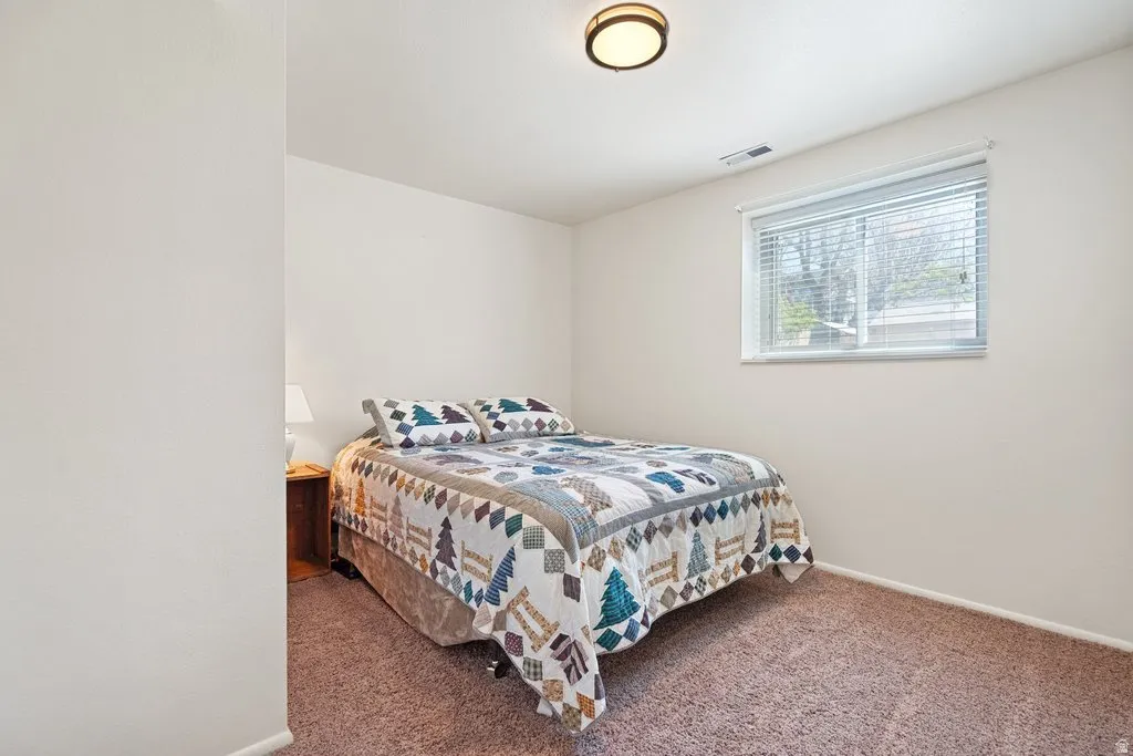 Bedroom featuring neutral tone walls, brown carpeting, and a window with blinds