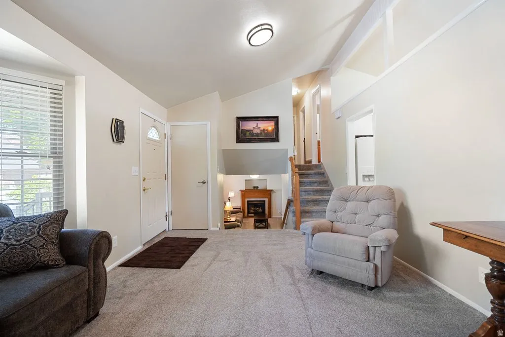 Inviting living space featuring vaulted ceilings, a prominent entry door with an arched window, and a lower-level fireplace