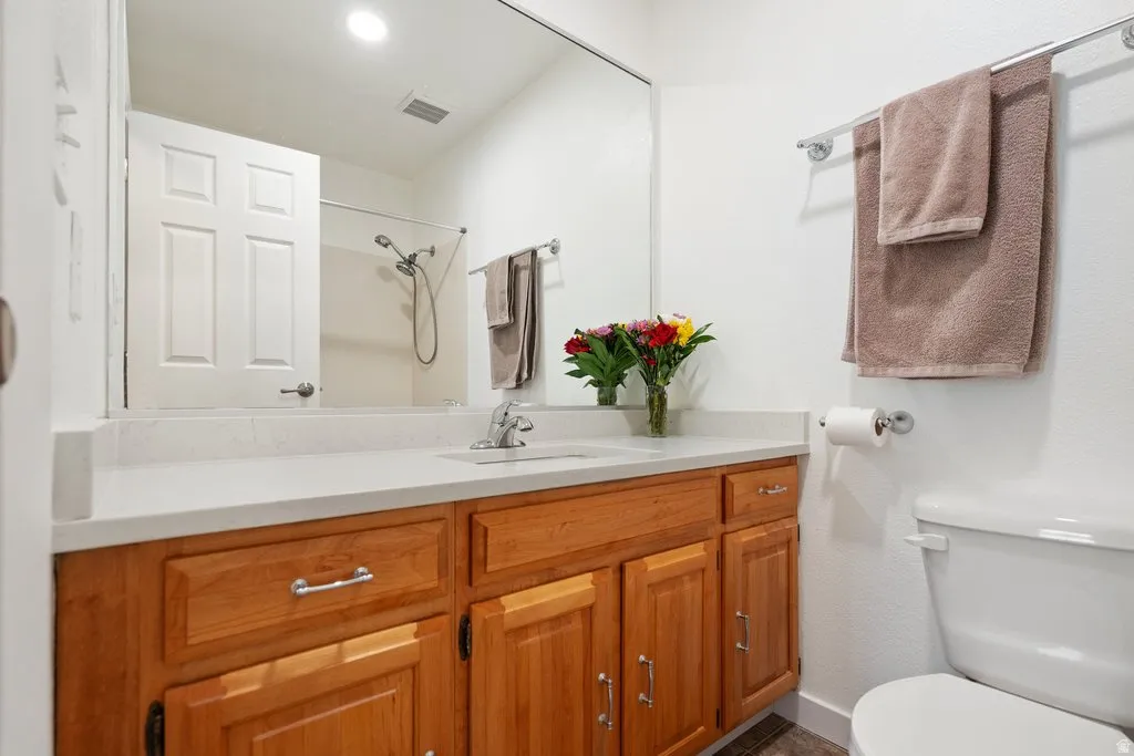 Bathroom featuring a wood-finish vanity with a light-colored countertop, integrated sink, and chrome fixtures