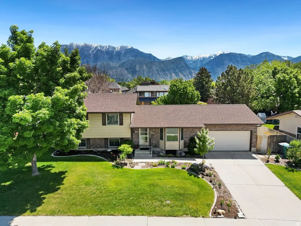Split-level residence featuring a two-car garage, established landscaping, and a concrete driveway