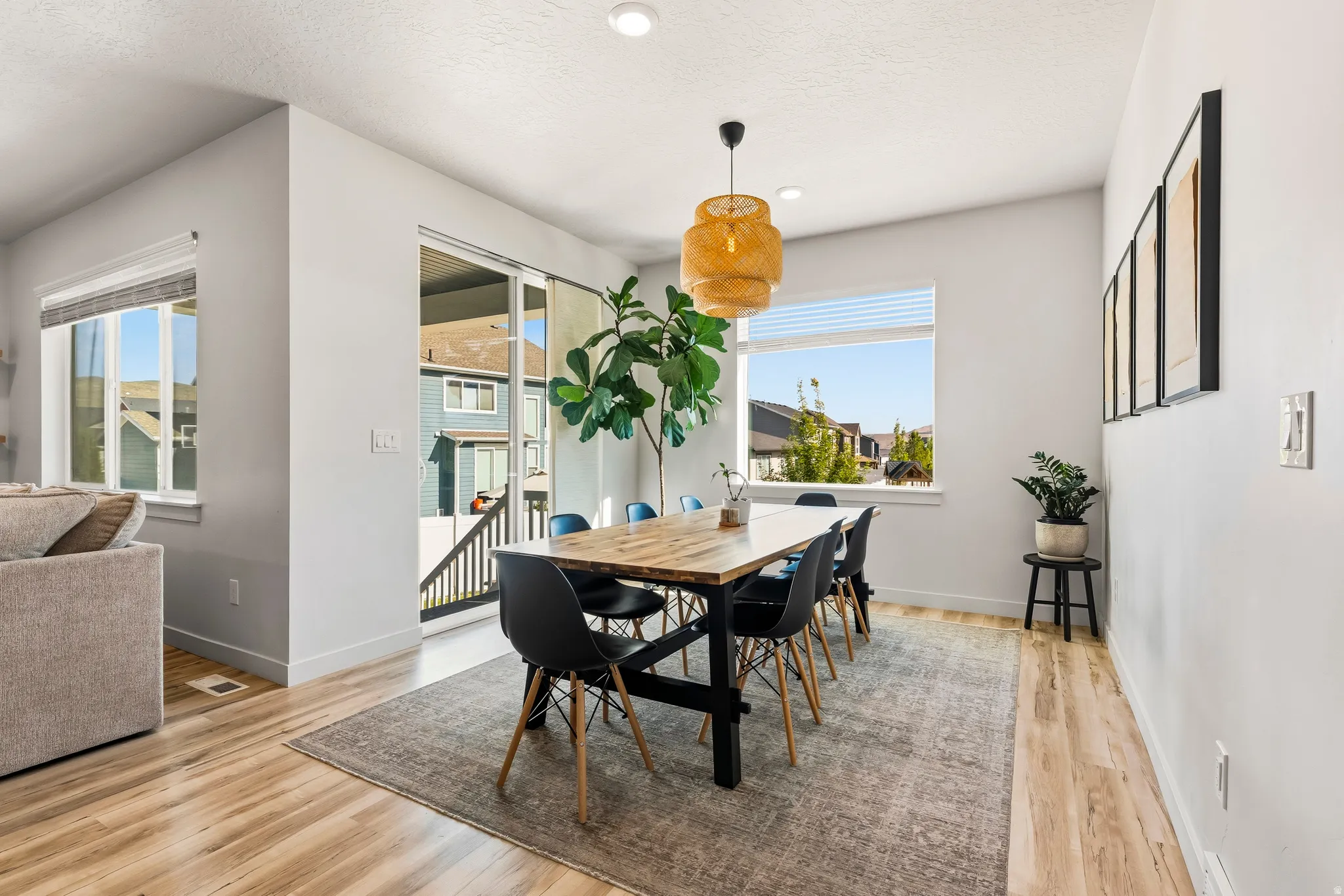 Open-concept dining area featuring wood-finish flooring, a contemporary pendant light fixture, and a sliding glass door providing outdoor access