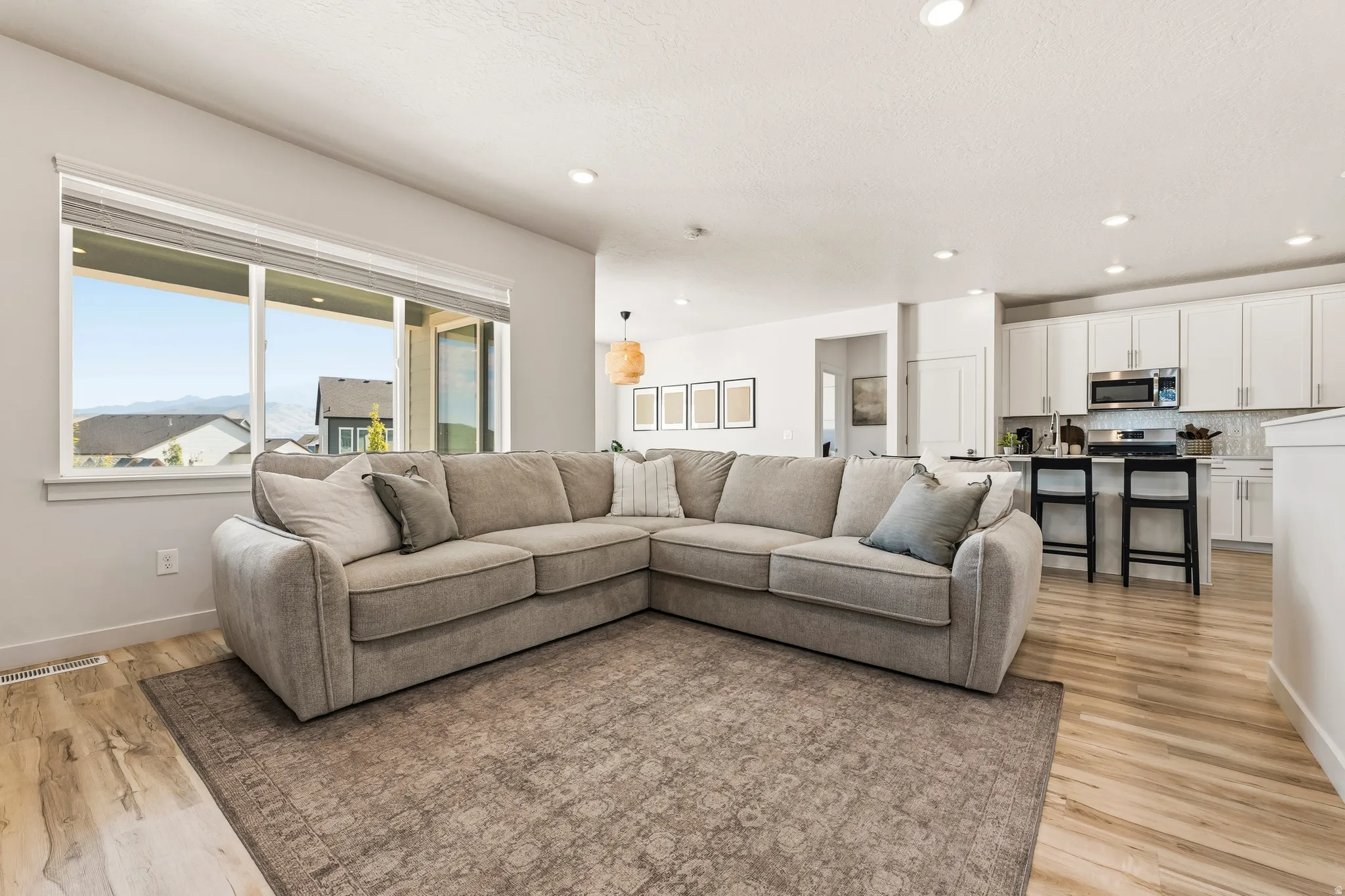 Open-concept living area with a large window, recessed lighting, and wood-finish flooring