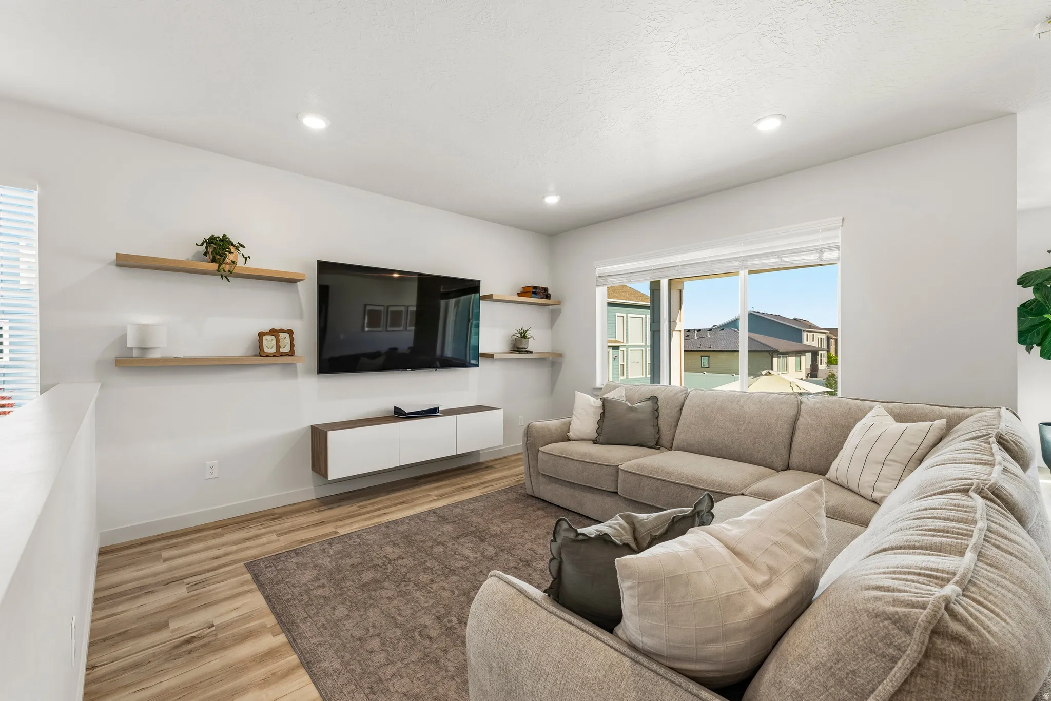 Living area featuring wood-finish flooring, recessed lighting, a built-in media console, and a large window