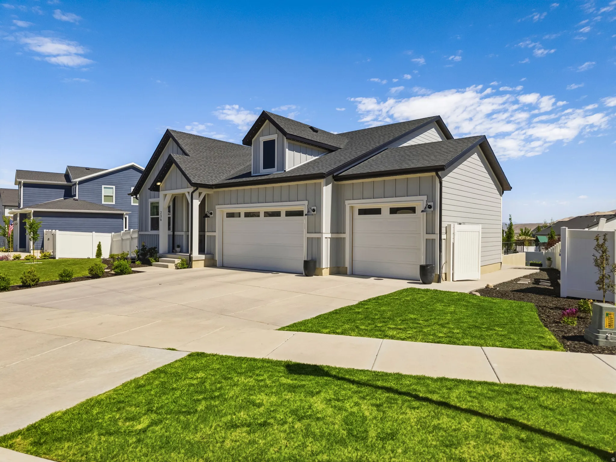 Contemporary two-story residence featuring light gray siding and a dark shingle roof