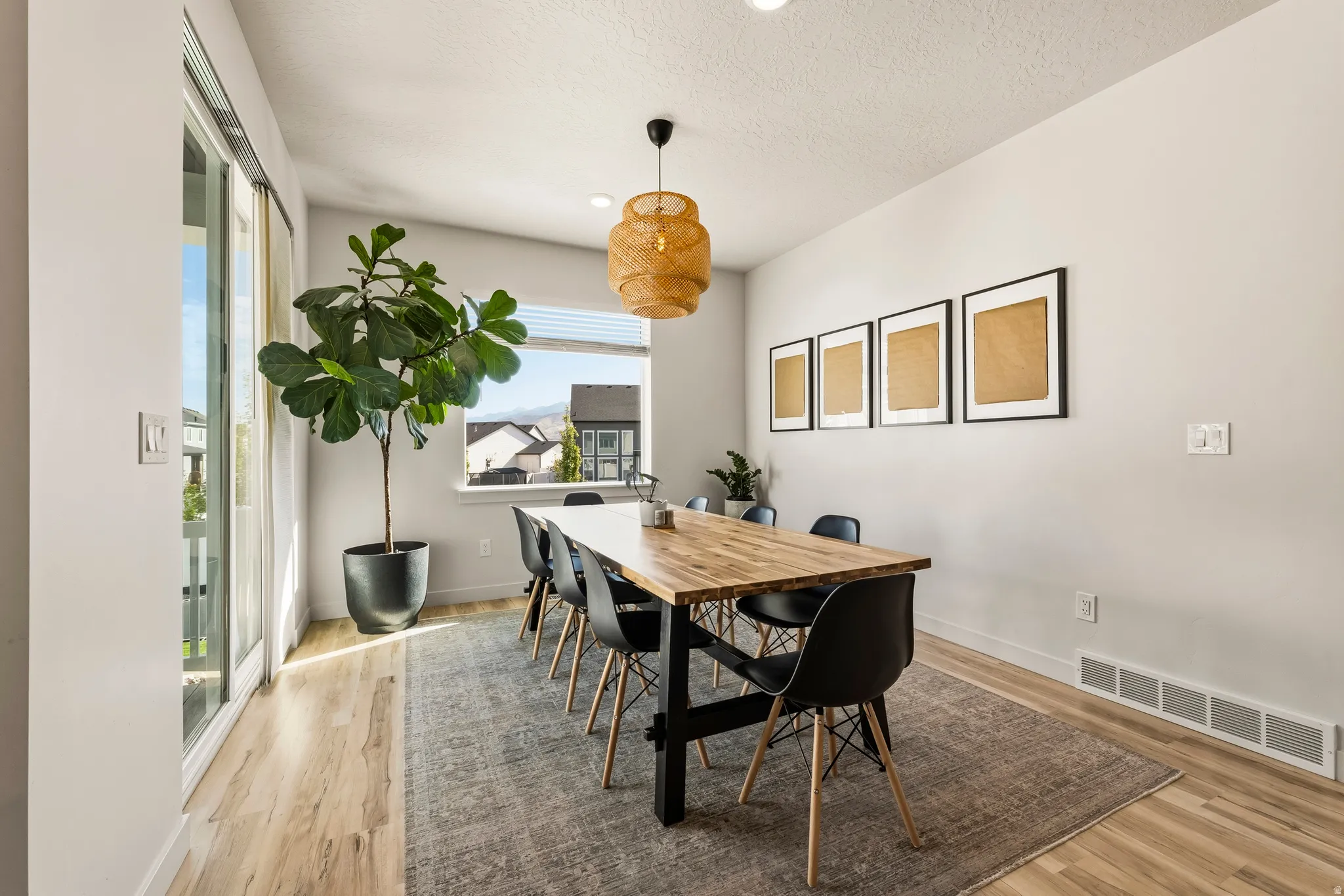 Dining area featuring wood-finish flooring, a contemporary ceiling light fixture, a large window, a sliding glass door, and recessed lighting