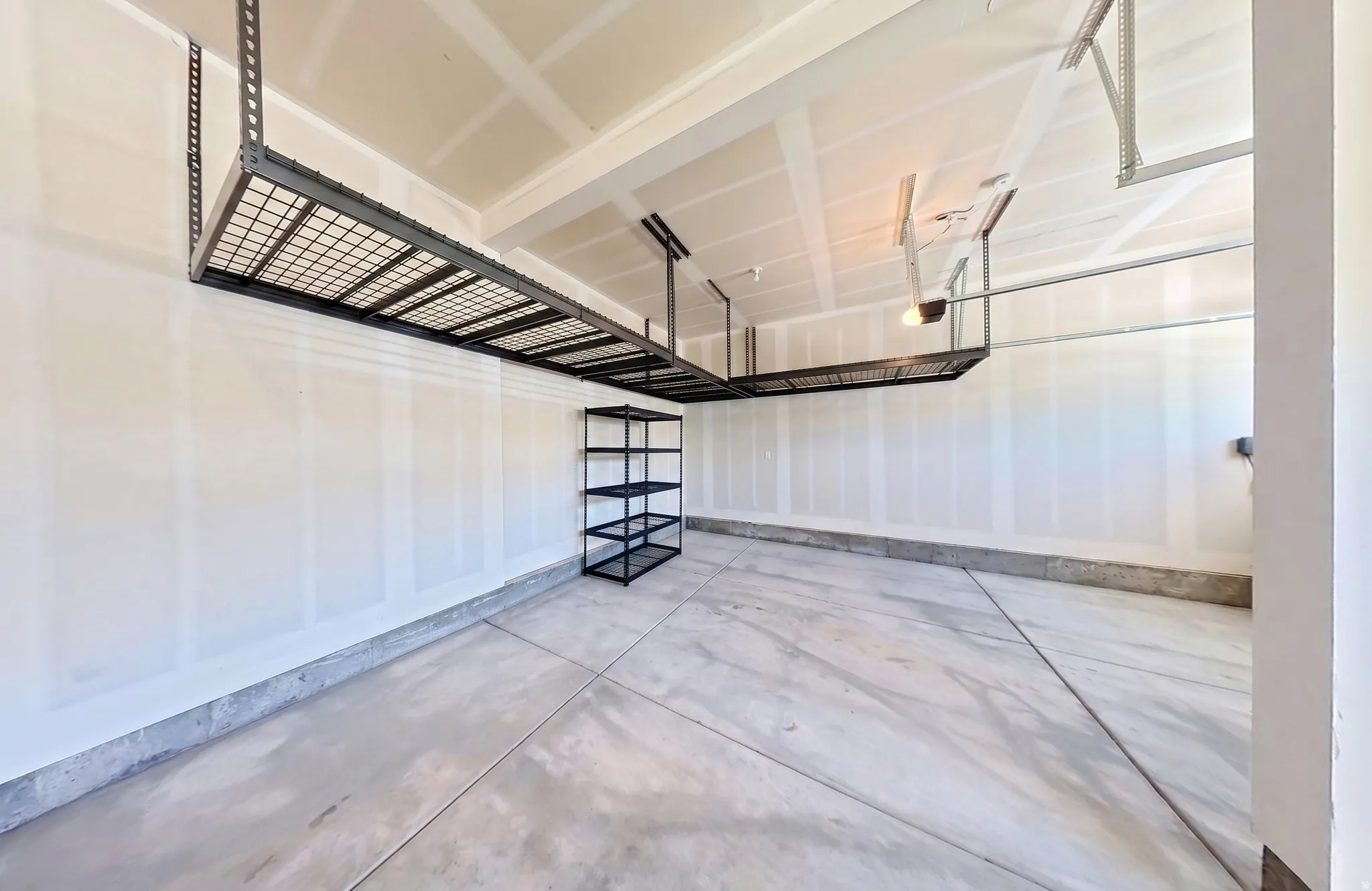 Spacious garage featuring concrete flooring and exposed ceiling rafters