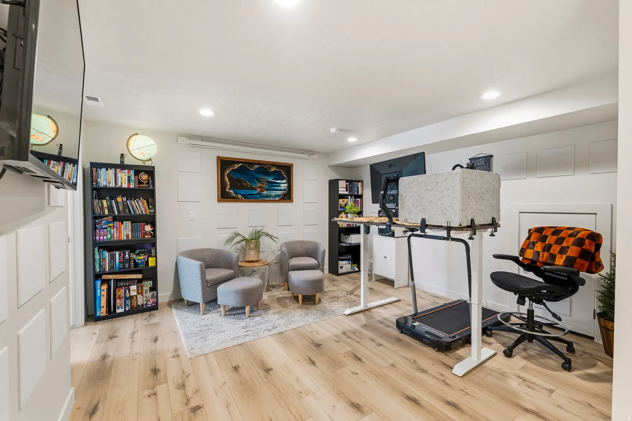Spacious room featuring light wood-finish flooring, recessed lighting, and white paneling