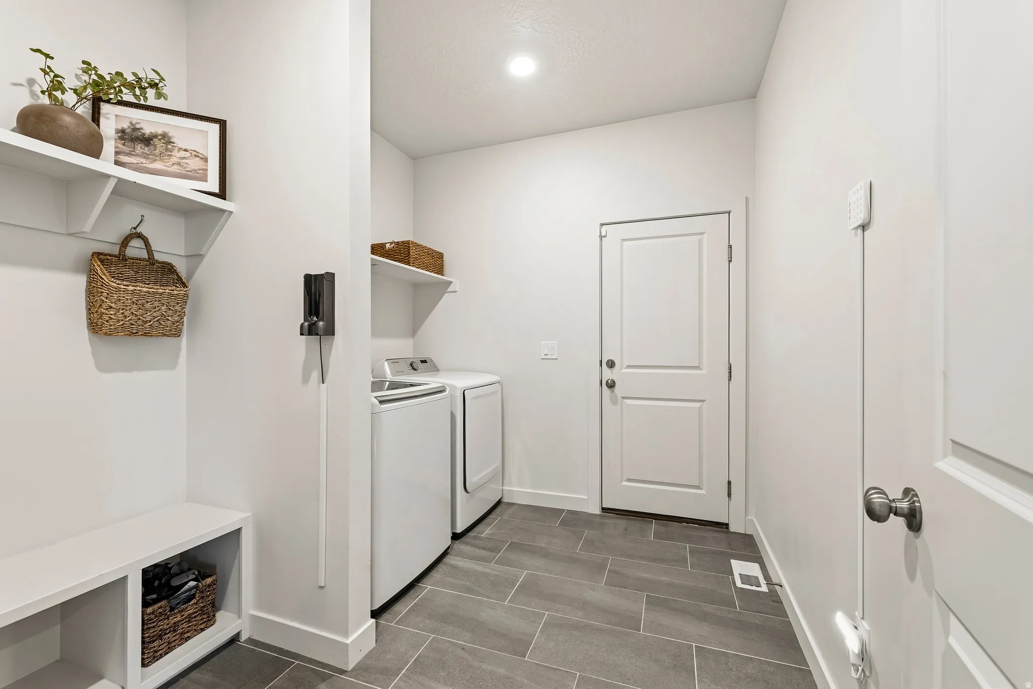 Laundry area featuring large format tile flooring, built-in shelving, and a two-panel interior door
