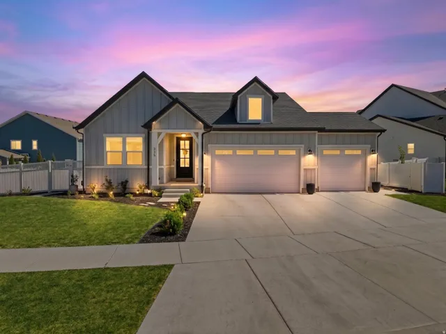 Modern farmhouse exterior with light gray vertical siding, a covered entry porch, and a dormer window