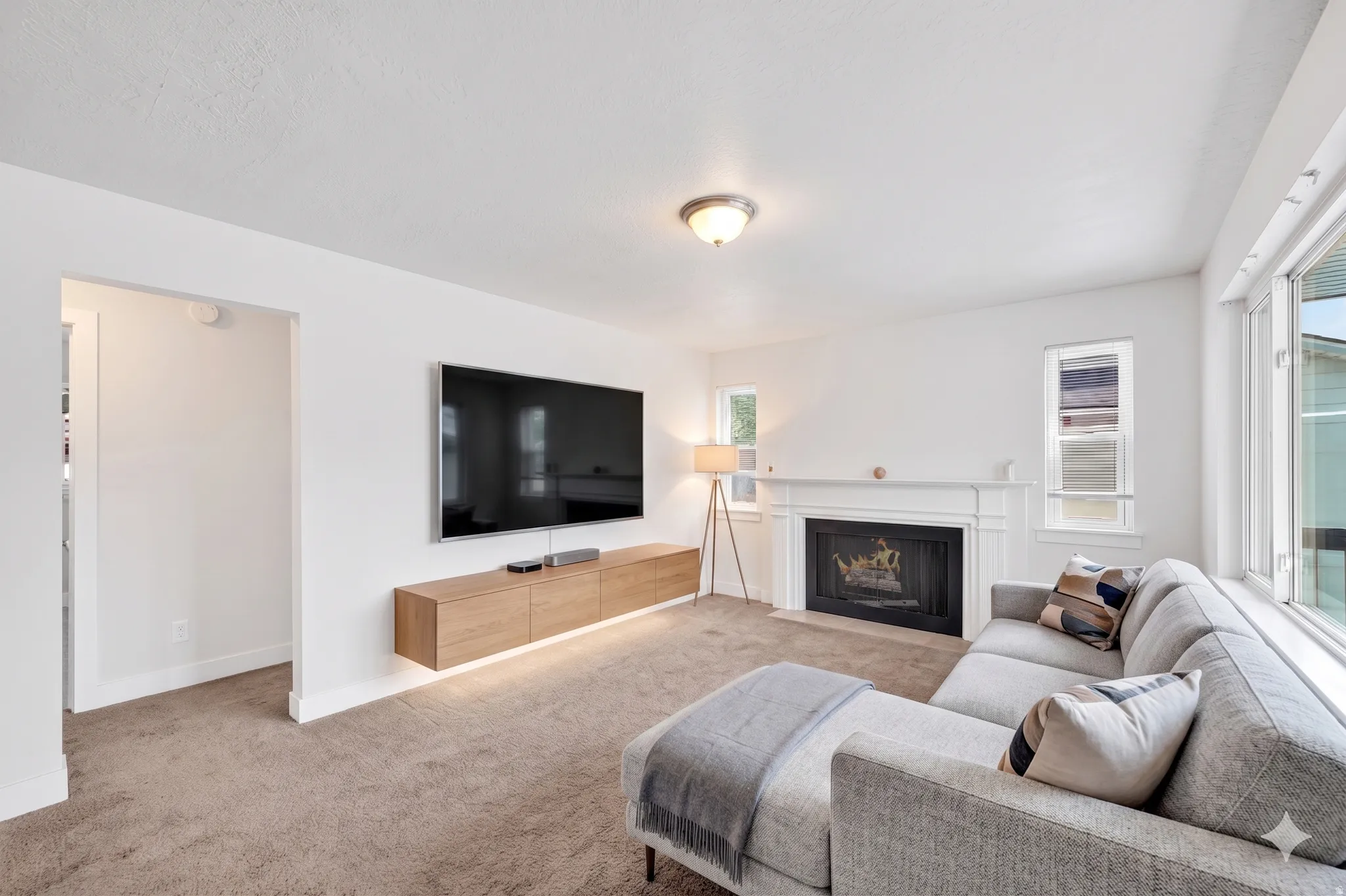 Living area featuring a white fireplace mantel and hearth, a wall-mounted media console, and a large window