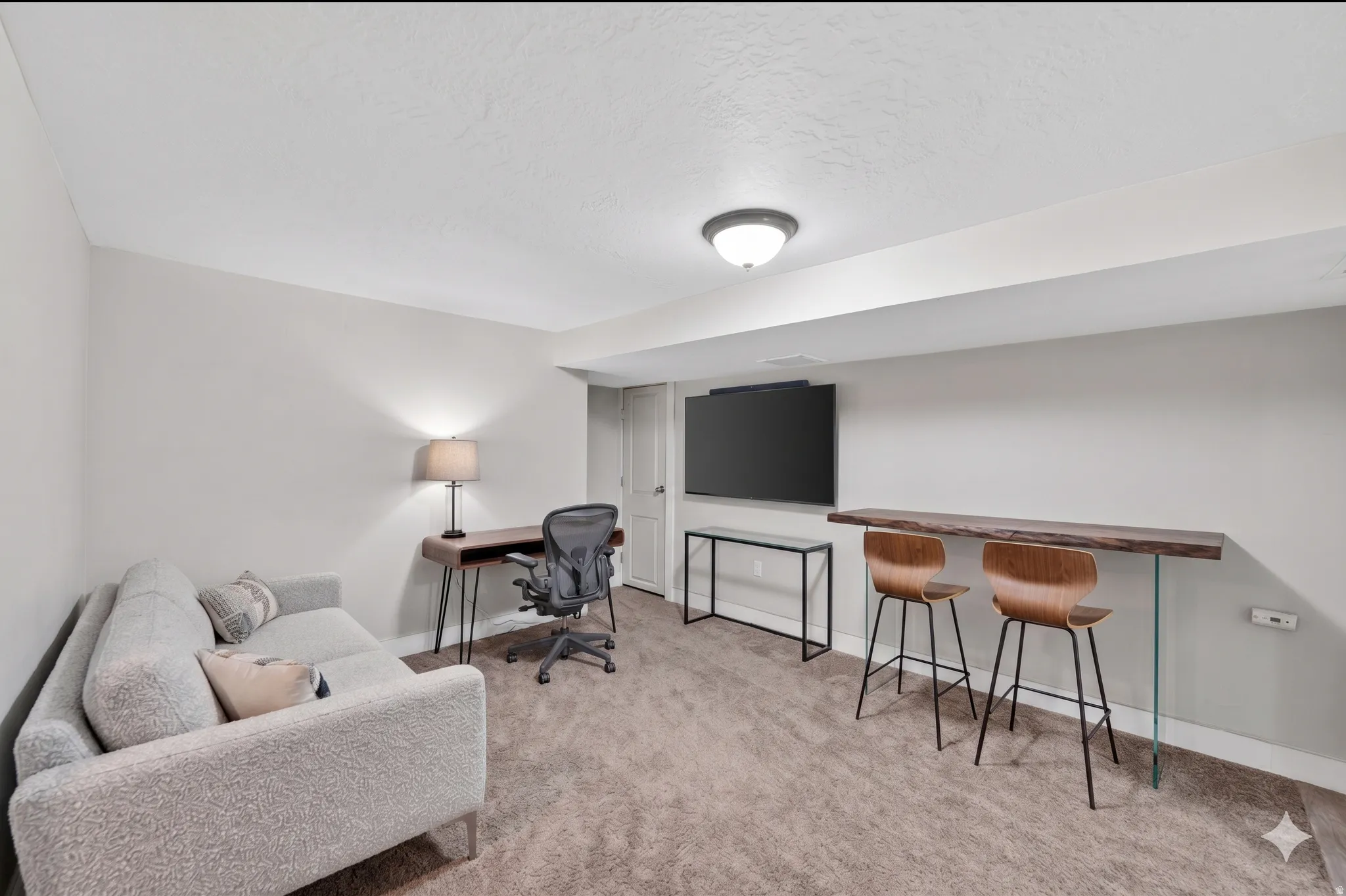 Finished basement featuring light gray walls, recessed lighting, and a built-in wood-finish bar top with clear supports