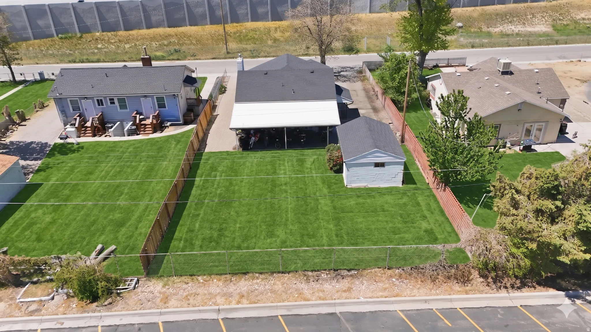 Expansive fenced yard featuring a well-maintained lawn, accompanied by a detached structure and covered patio space