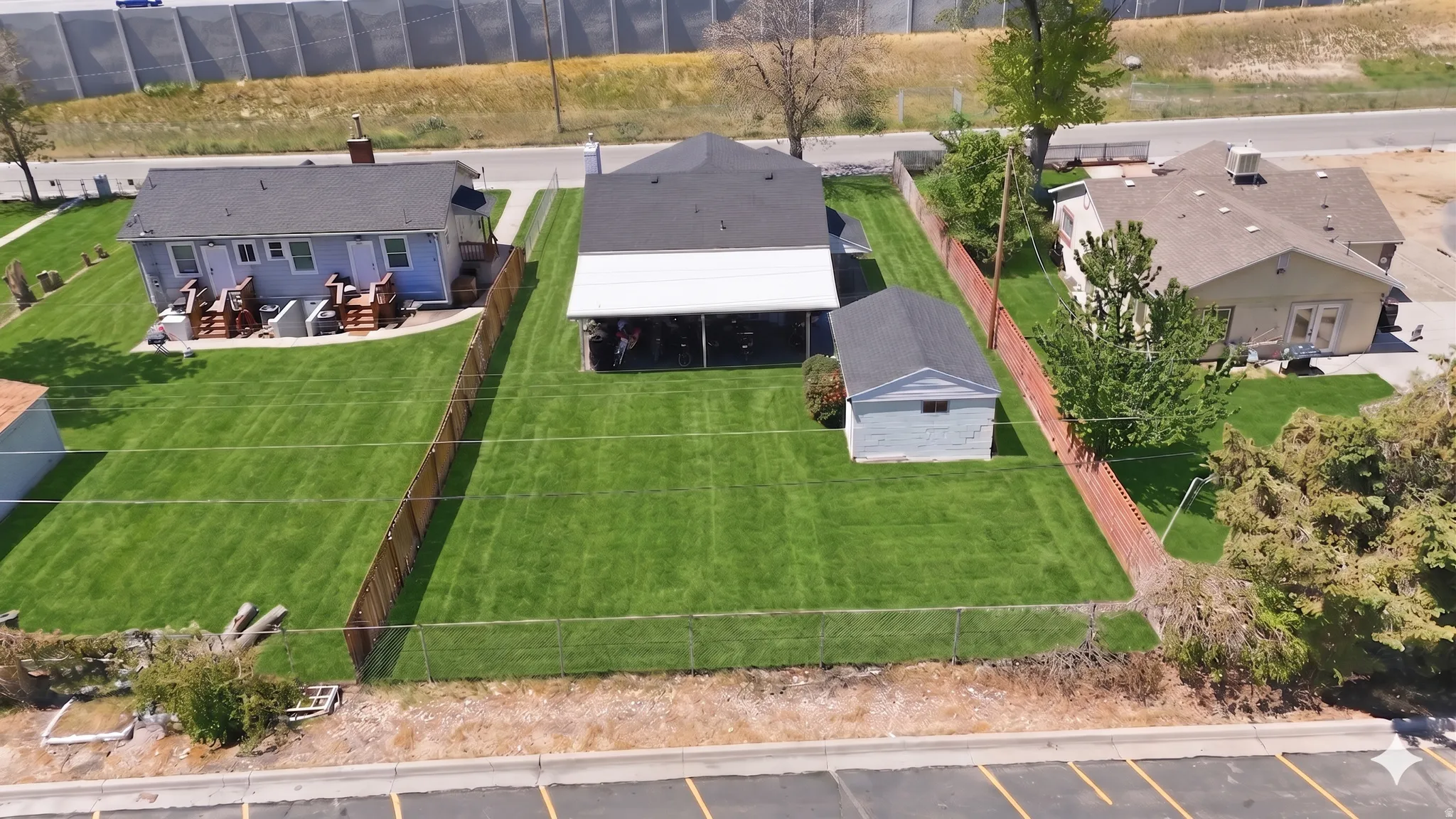 Expansive, fenced backyard featuring a detached garage, a covered patio area, and a manicured lawn