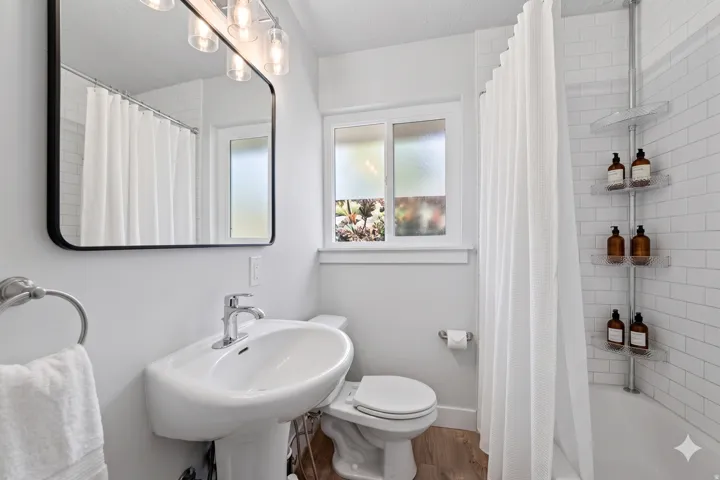 Bathroom featuring a pedestal sink, chrome fixtures, and a rectangular mirror with an overhead light bar