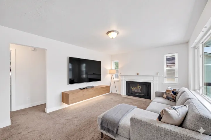 Living area featuring a white fireplace mantel and hearth, a wall-mounted media console, and a large window