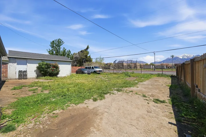 Spacious rear yard featuring a detached garage, partial wood fencing, and mountain scenery