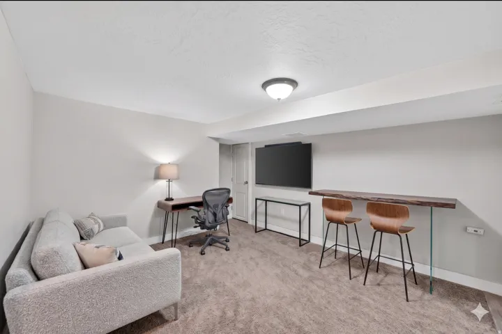 Finished basement featuring light gray walls, recessed lighting, and a built-in wood-finish bar top with clear supports