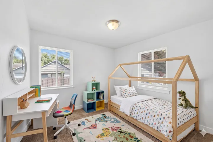 Bright room featuring two windows with blinds, a built-in flush-mount ceiling light fixture, and neutral-toned wall-to-wall carpeting