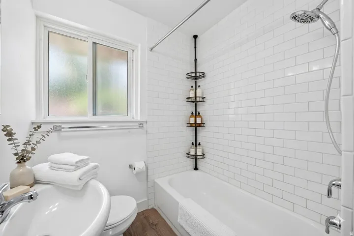 Bathroom featuring a full tub with subway tile surround, chrome fixtures, and a shower head with hose attachment