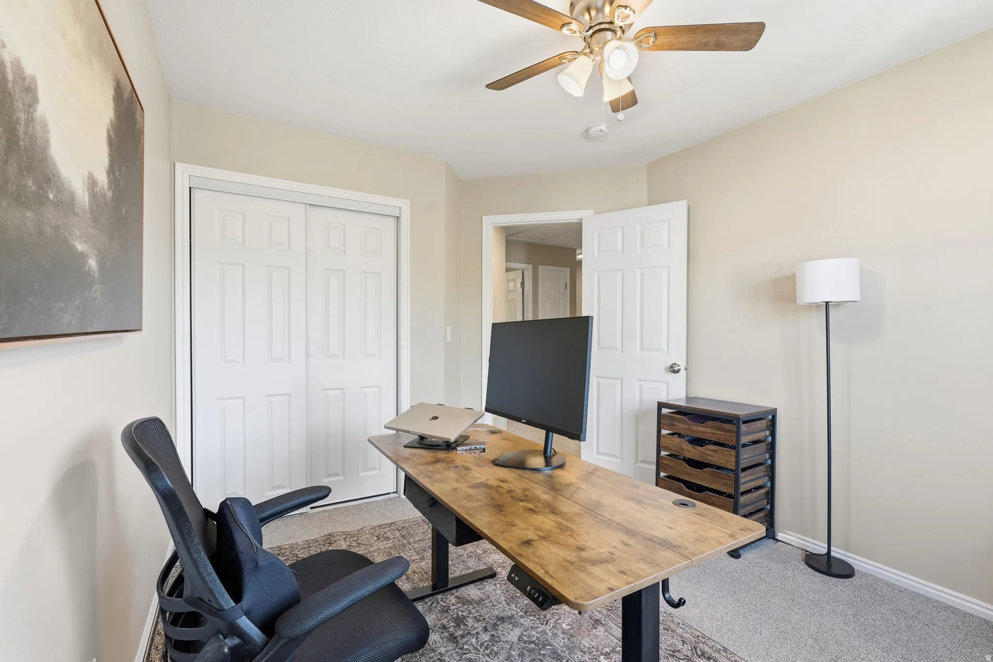 Neutral-toned room featuring a ceiling fan with integrated lighting, paneled doors, and carpeted flooring