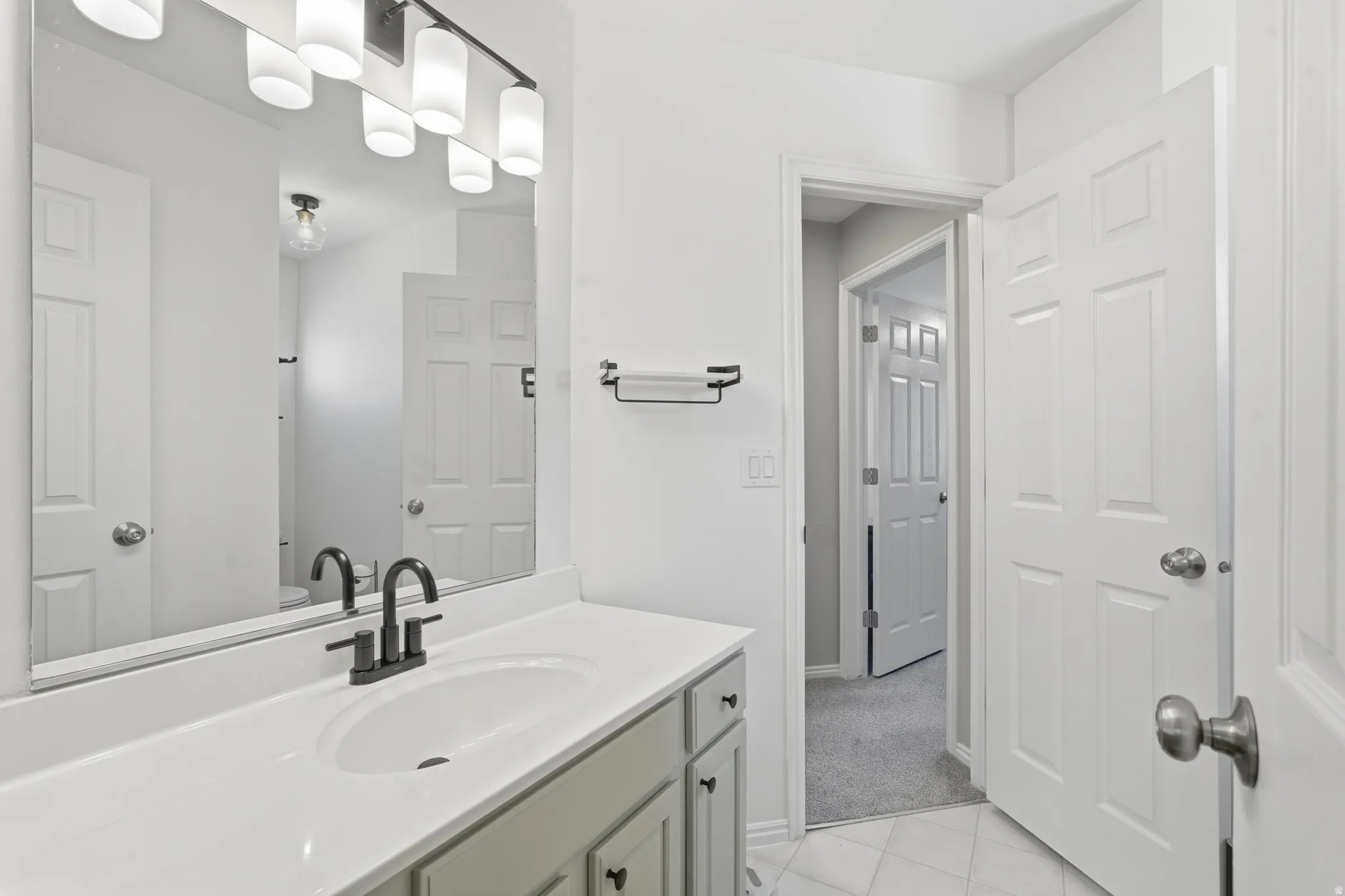 Bathroom vanity featuring an integrated sink, white countertop, and matte black faucet