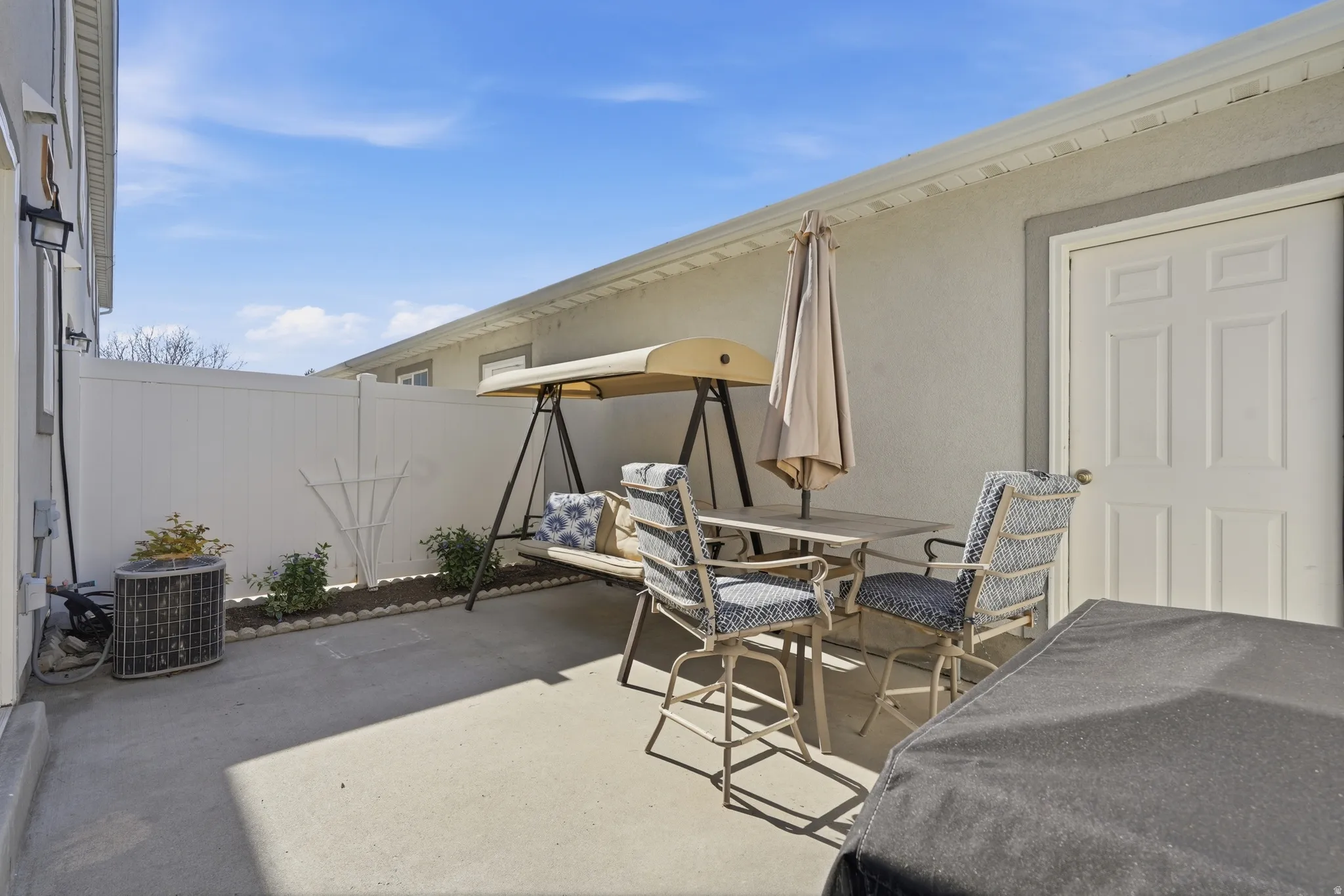 Private concrete patio area featuring a white privacy fence and a white panel door
