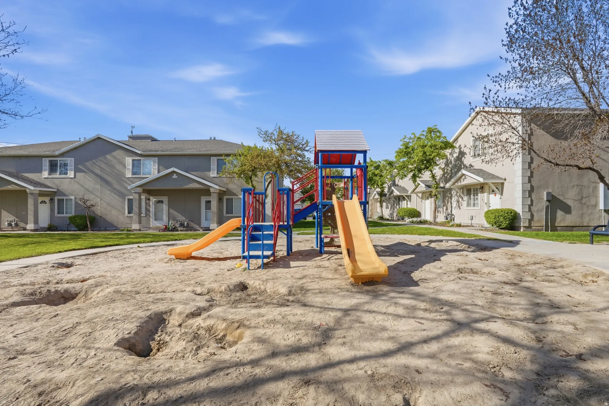 Community playground featuring a sand base, two slides, and climbing structures