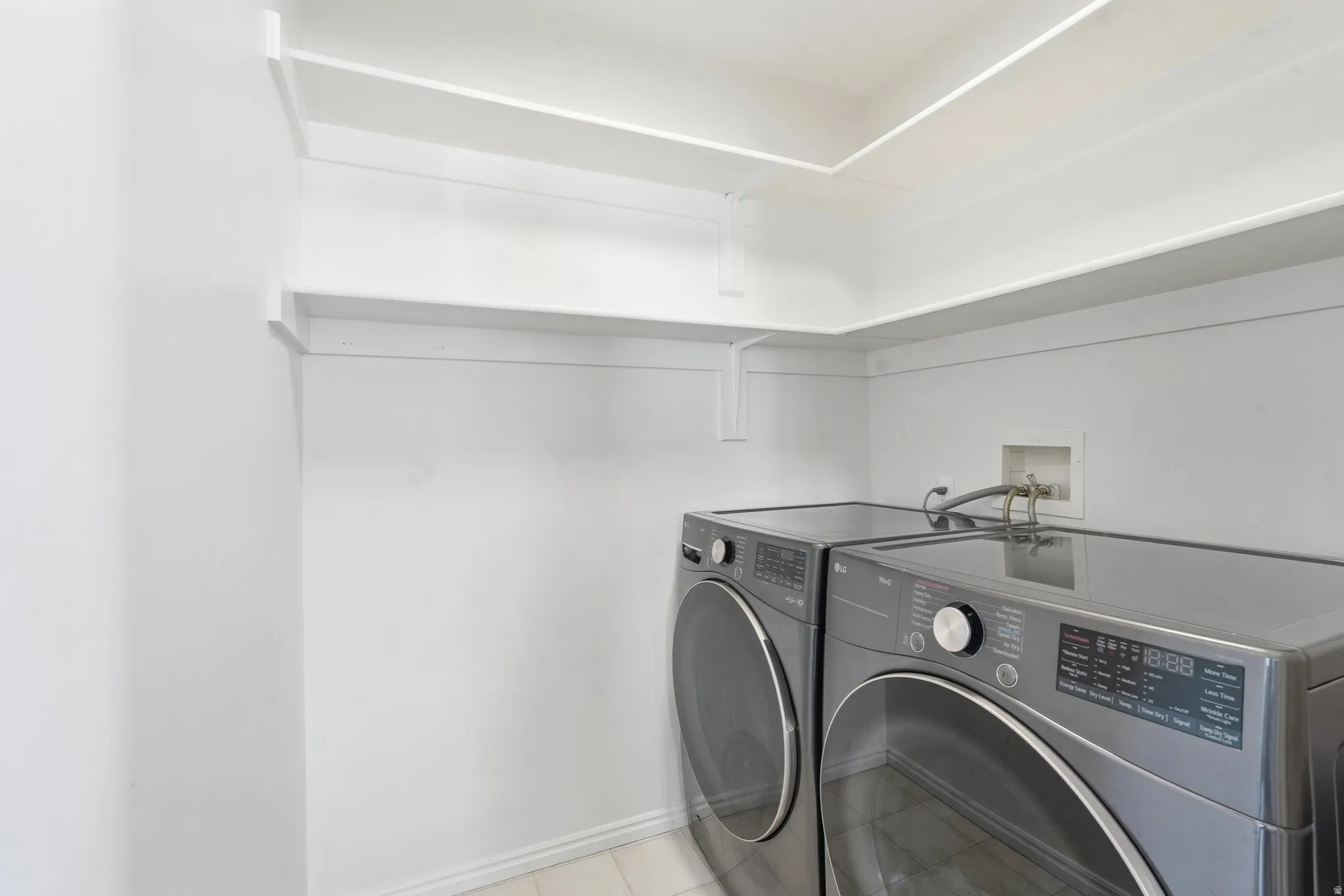 Dedicated laundry area featuring white shelving and baseboards