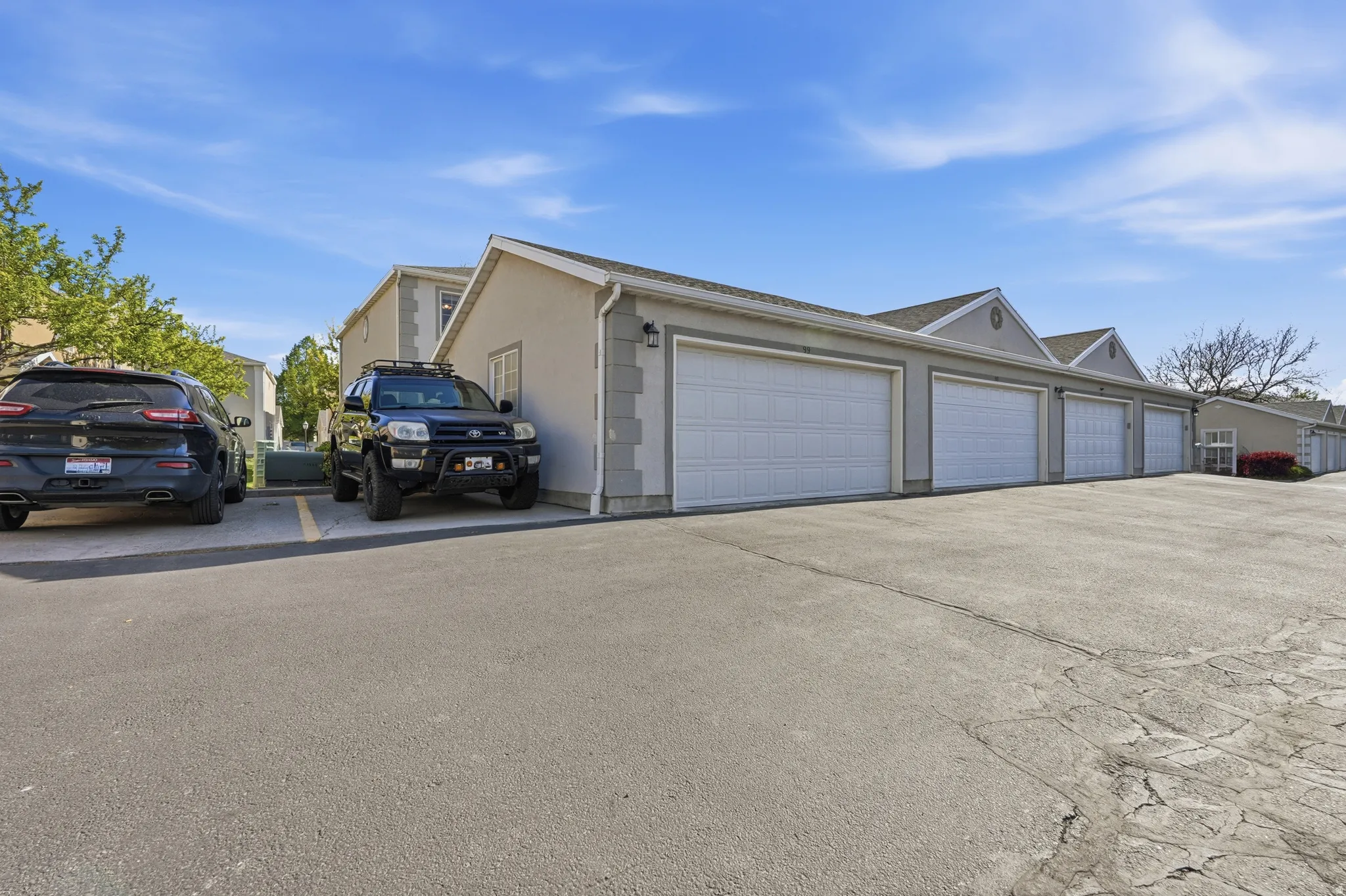 Multiple attached garages with white panel doors and stucco exteriors