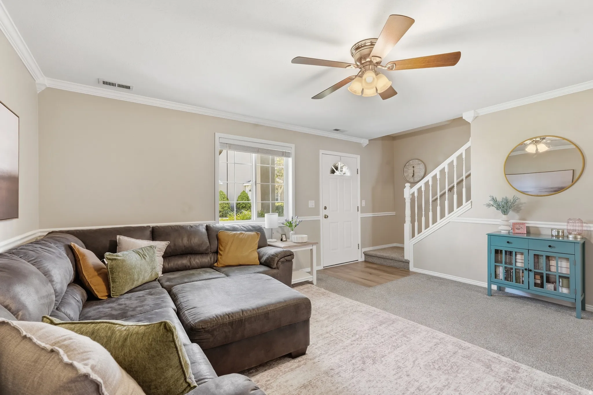 Living area featuring neutral wall tones, crown molding, a ceiling fan, and a front entry door with decorative glass