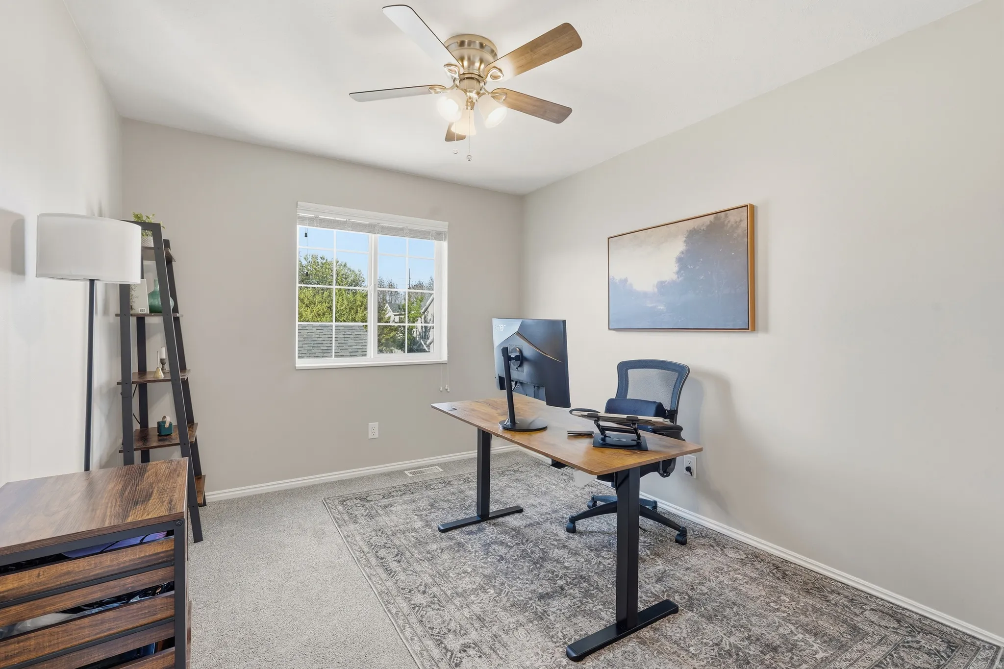 Bright room featuring a window with grid inserts, light gray wall paint, and a ceiling fan with light fixture
