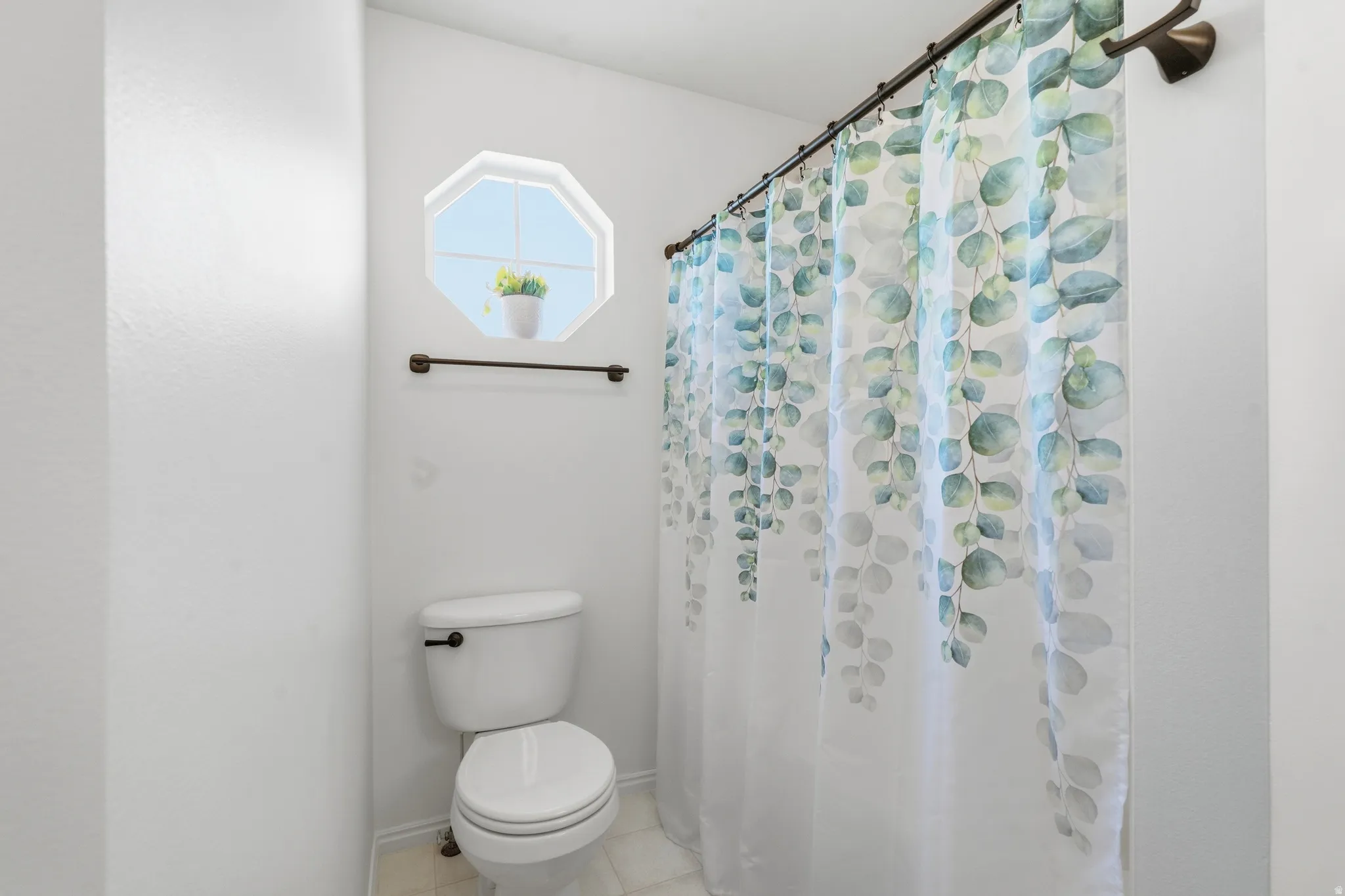 Bathroom featuring an octagonal window, white toilet, and bronze-finish fixtures