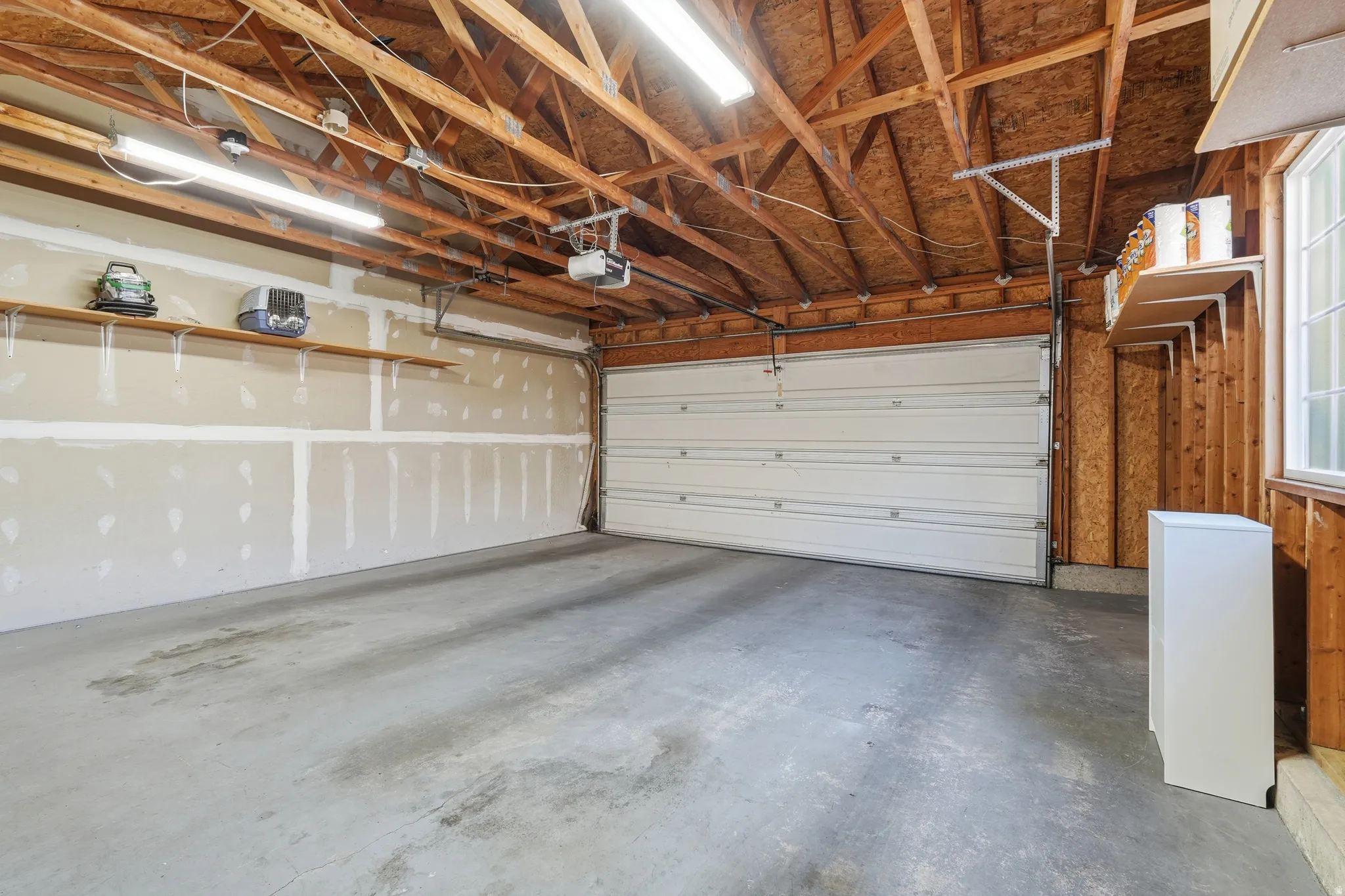 Spacious two-car garage with a concrete floor and exposed wood beam ceiling
