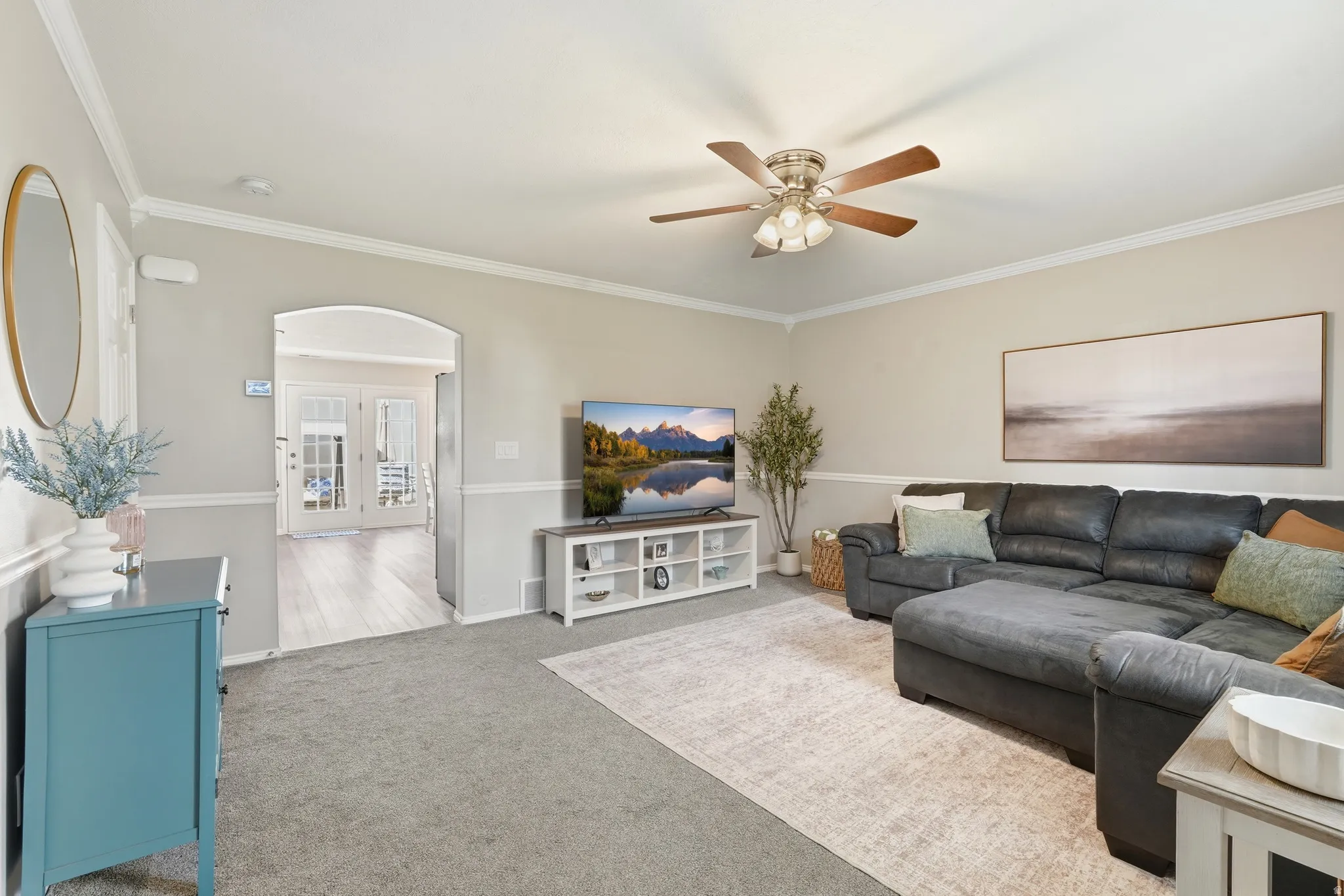 Living area featuring neutral wall paint, white crown molding, and wainscoting