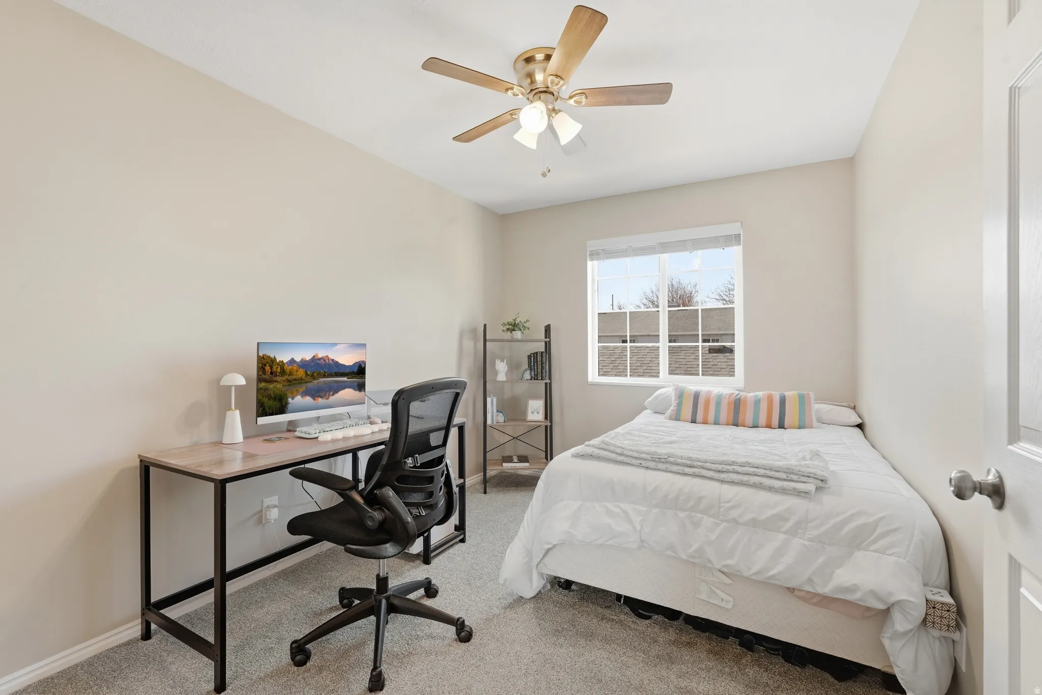Neutral tone wall paint, textured carpeting, a multi-pane window with blinds, and a brass-finish ceiling fan with lighting