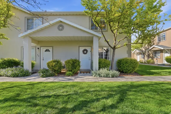 Cream-colored stucco exterior featuring a covered porch entrance with white columns