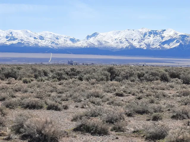 Expansive desert landscape featuring natural scrub brush and gravel terrain