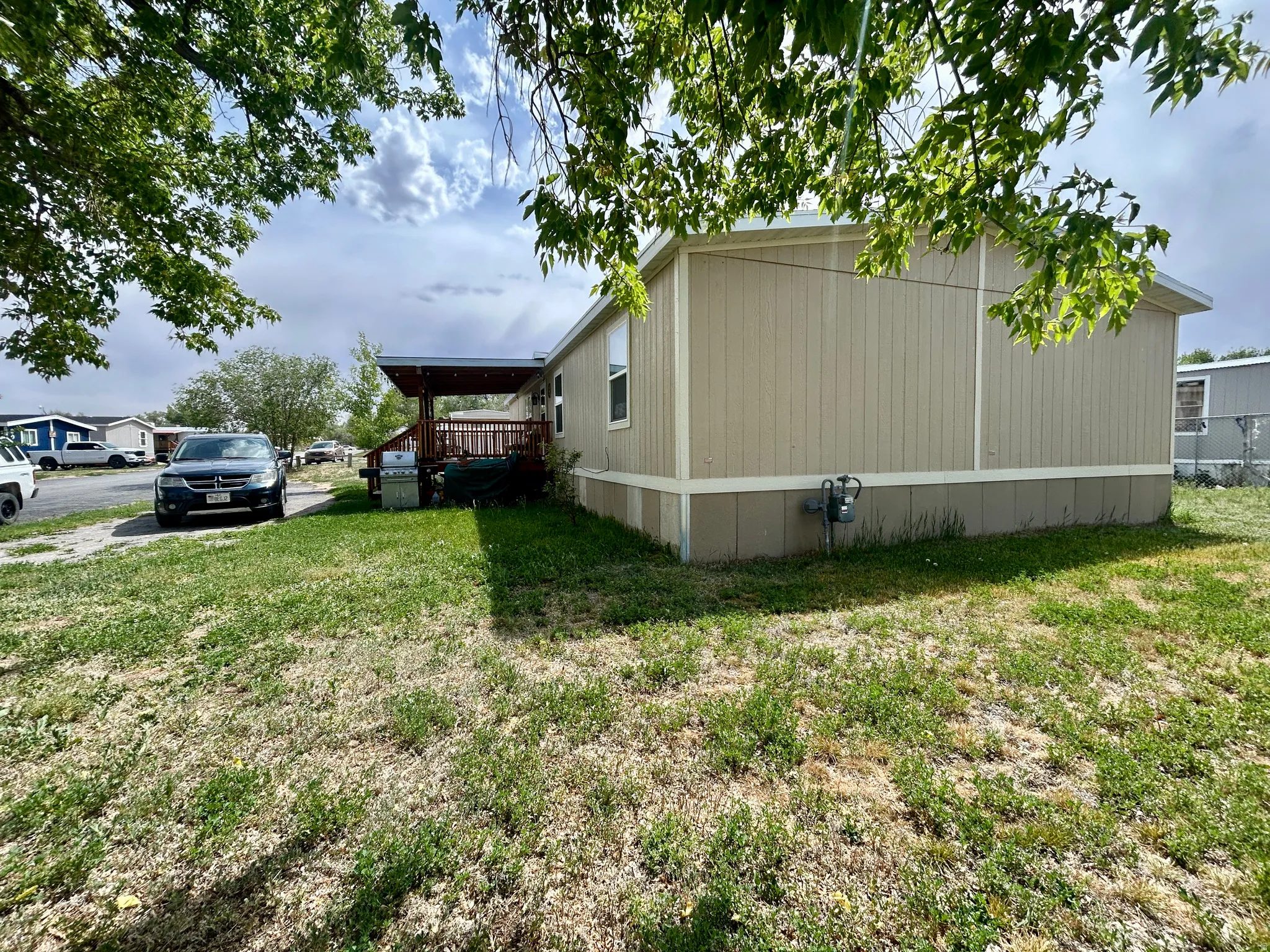 Expansive side yard with a covered outdoor deck featuring wood-finish decking and a built-in railing
