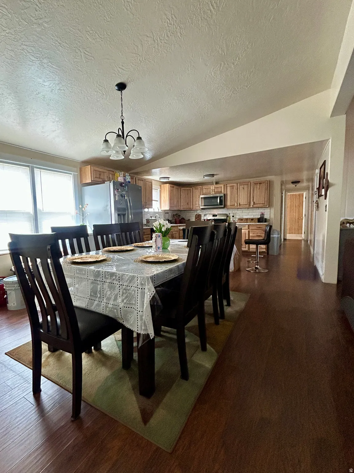 Open-concept dining and kitchen area featuring wood-finish flooring, recessed lighting, and a large window