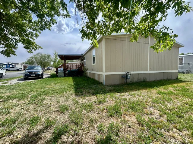 Expansive side yard with a covered outdoor deck featuring wood-finish decking and a built-in railing