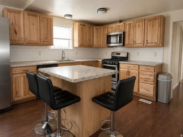 Kitchen featuring wood cabinetry, light-toned countertops, a subway tile backsplash, stainless steel appliances, and wood-finish flooring