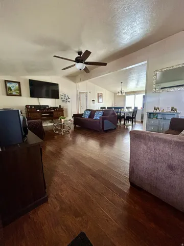 Open-concept living area featuring wood-finish flooring, a ceiling fan, and sloped ceilings