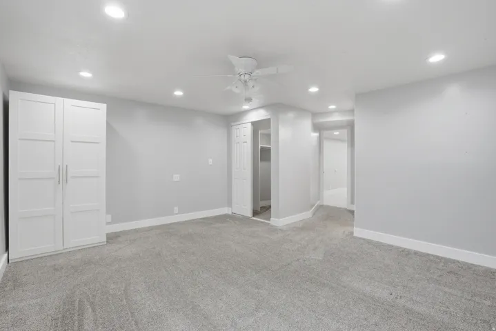 Carpeted interior room featuring recessed lighting, a ceiling fan, base molding, a built-in white wardrobe, and a white bi-fold closet door