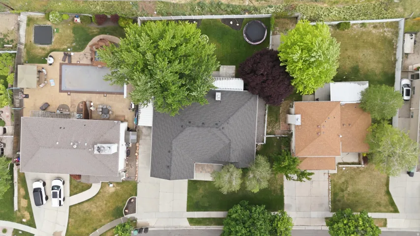 Expansive backyard with a large inground pool, extensive hardscaping, mature trees, and a private patio area