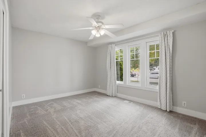 Expansive room featuring light gray wall paint and a coordinating patterned carpet